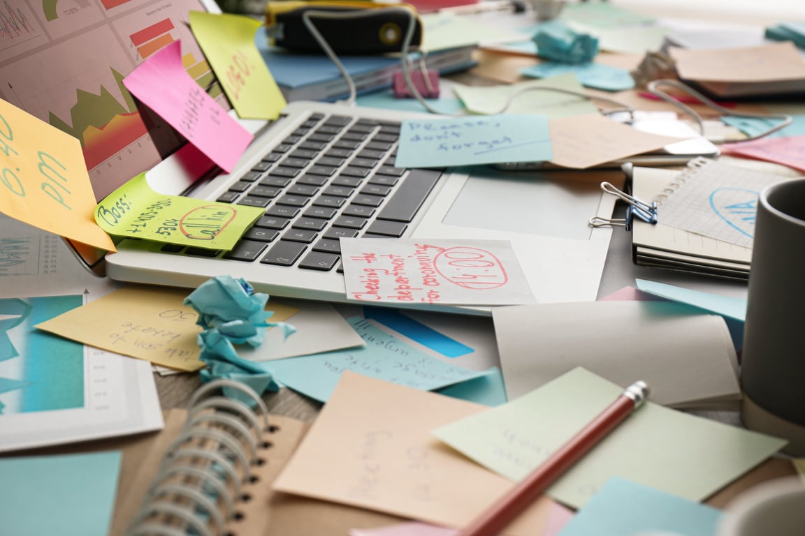 Laptop, Notes and Office Stationery in Mess on Desk. Overwhelmed